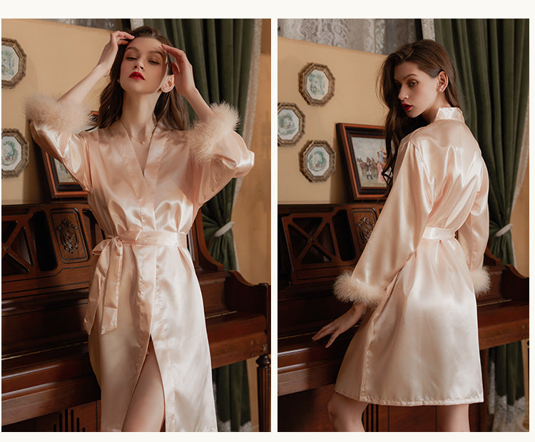 Satin robe with fur trim, featuring a belted waist and elegant design, displayed on a model in an indoor setting.