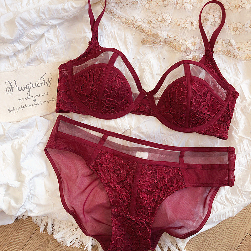 Burgundy lace lingerie set featuring a sheer bra with intricate floral patterns and matching panties, elegantly displayed on a textured background.