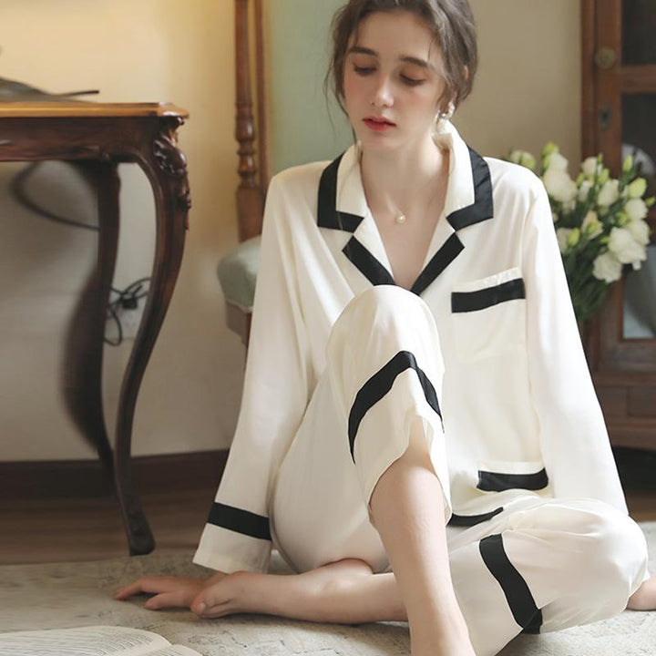 Elegant white silk pajamas with black trim, featuring a relaxed fit and classic button-down design, perfect for stylish nights in.