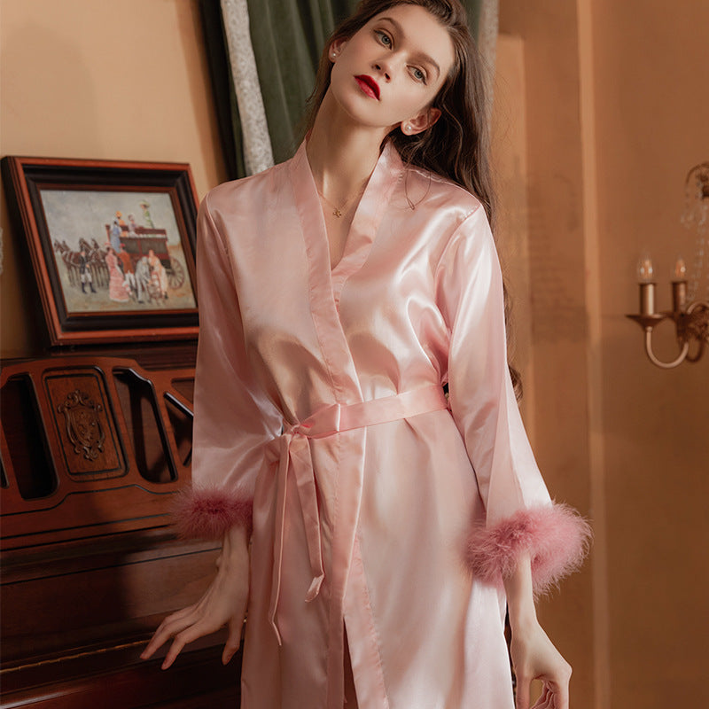 Elegant pink satin robe with fluffy cuffs, styled for a luxurious and romantic experience. Perfect for lingerie and nightwear collections.