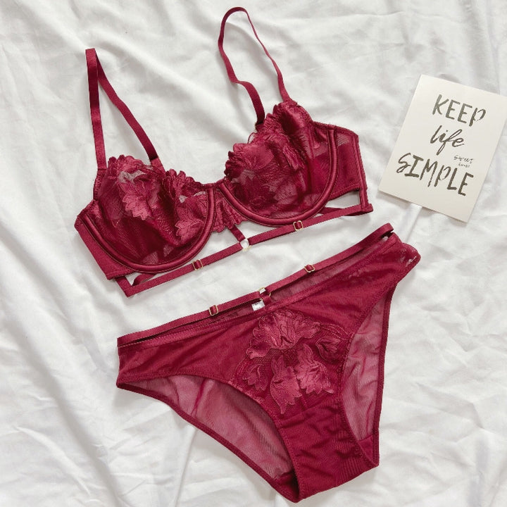 Luxe burgundy lace lingerie set featuring a delicate lace bra with floral detailing and matching sheer panties, elegantly styled on a soft white background.
