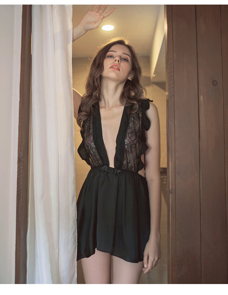 Lace-trimmed black lingerie nightgown with a deep V-neck and flirty ruffle detailing, showcasing a model in a softly lit setting.
