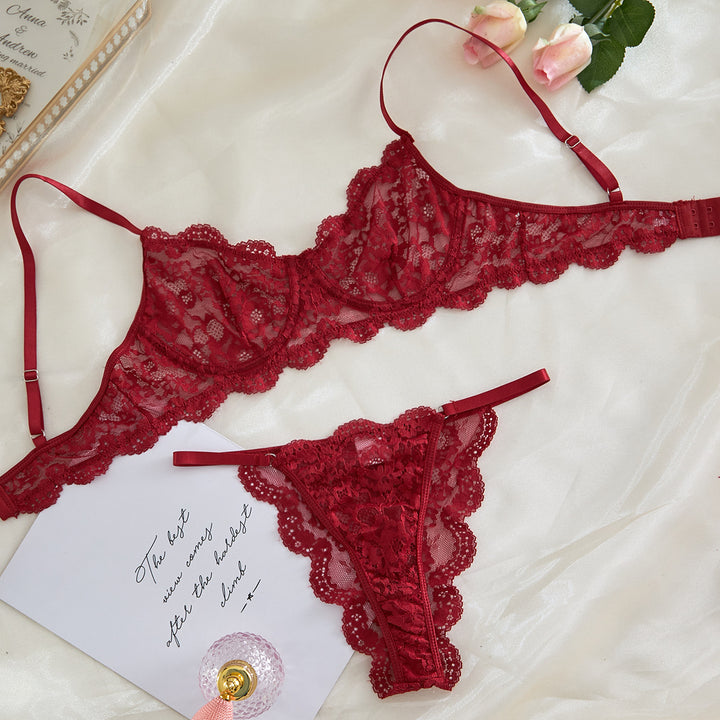 Red lace lingerie set featuring a bralette and matching thong, elegantly displayed on satin fabric with a floral accent and a handwritten note, perfect for romantic occasions