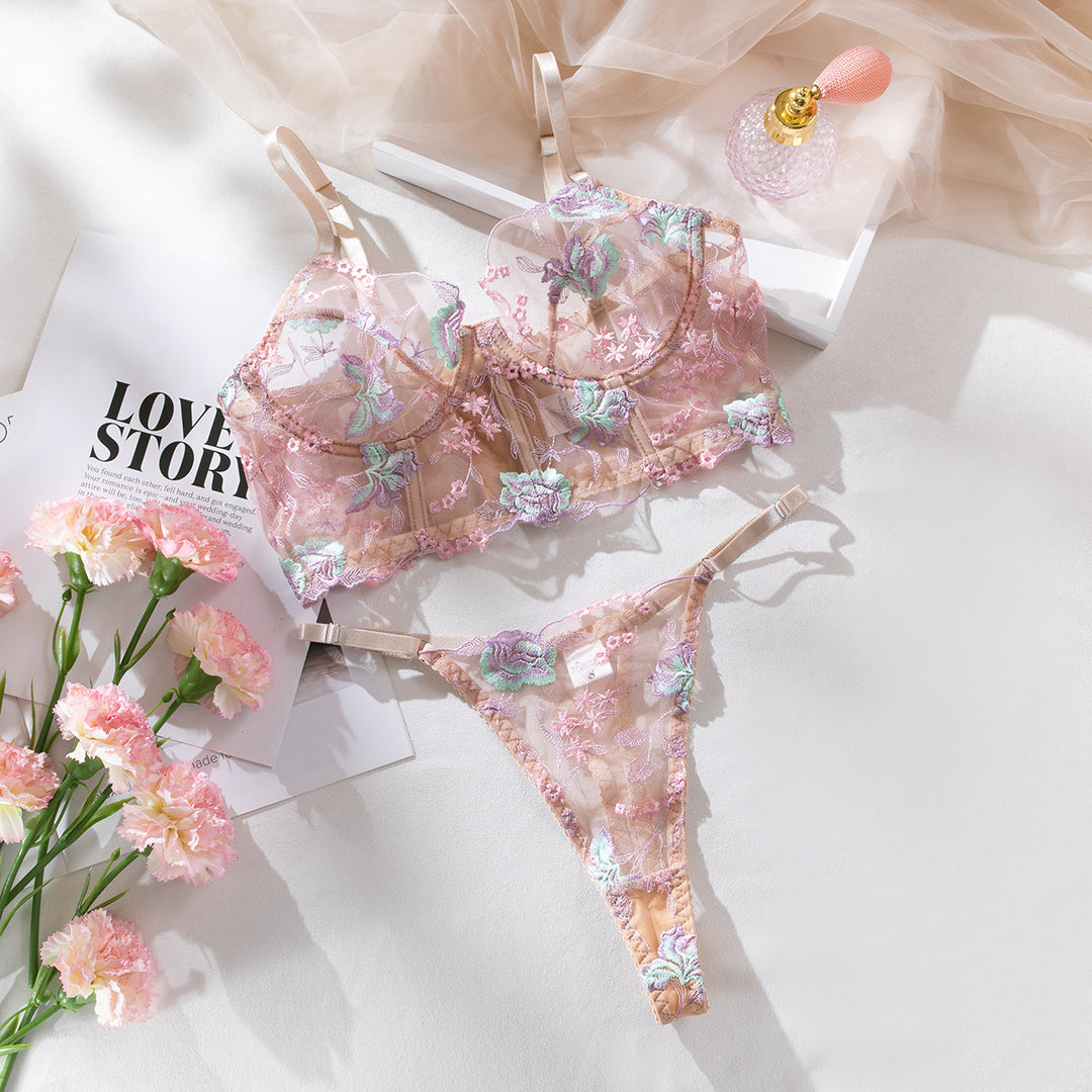 Lacey pink lingerie set featuring a floral embroidered bralette and matching thong, elegantly displayed with pink carnations and a perfume bottle, perfect for romantic occasions and