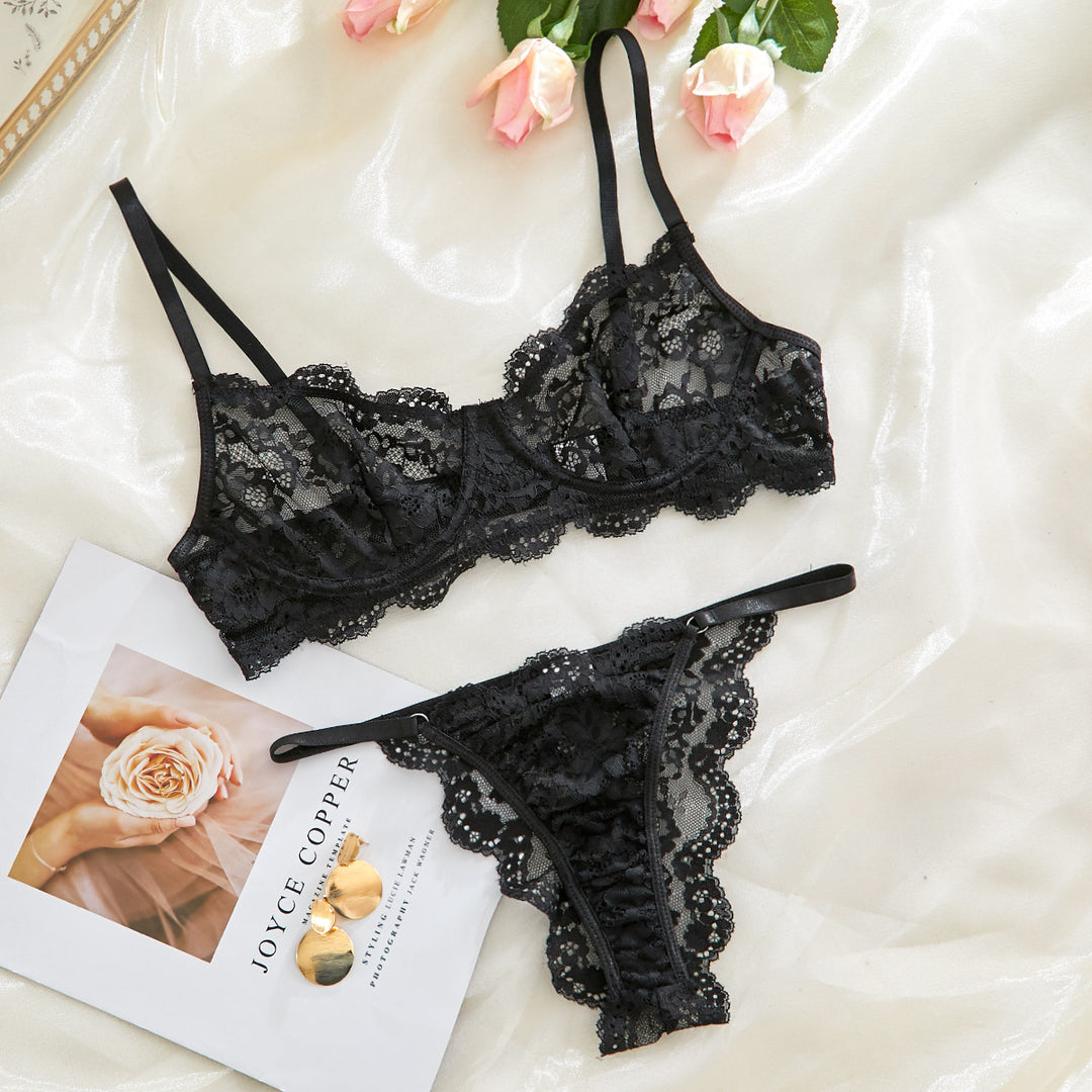 Black lace lingerie set featuring a delicate bralette and matching thong, displayed elegantly on a soft satin background with pink roses and a stylish magazine. Perfect for