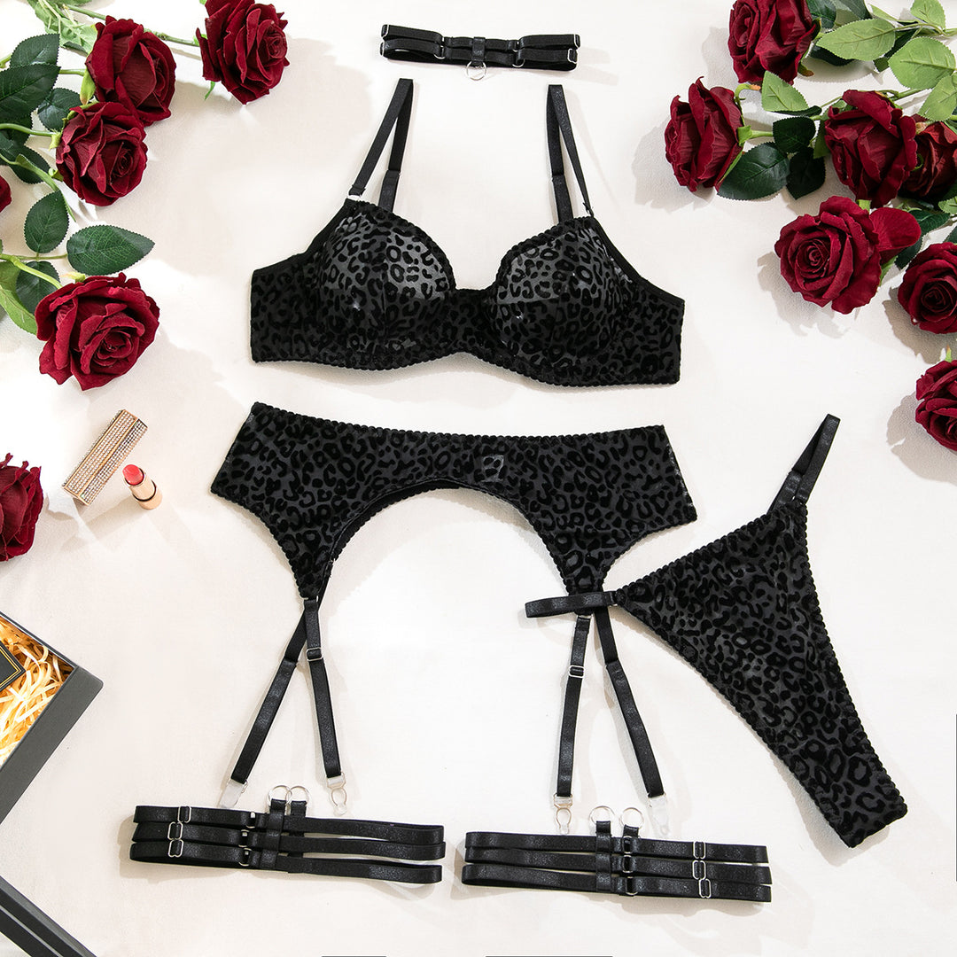 Black leopard print lingerie set featuring a bra, garter belt, and thong, styled with black straps and surrounded by red roses.