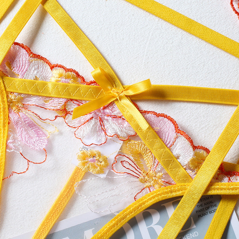 Delicate yellow lingerie with floral embroidery and ribbon details on a textured background.