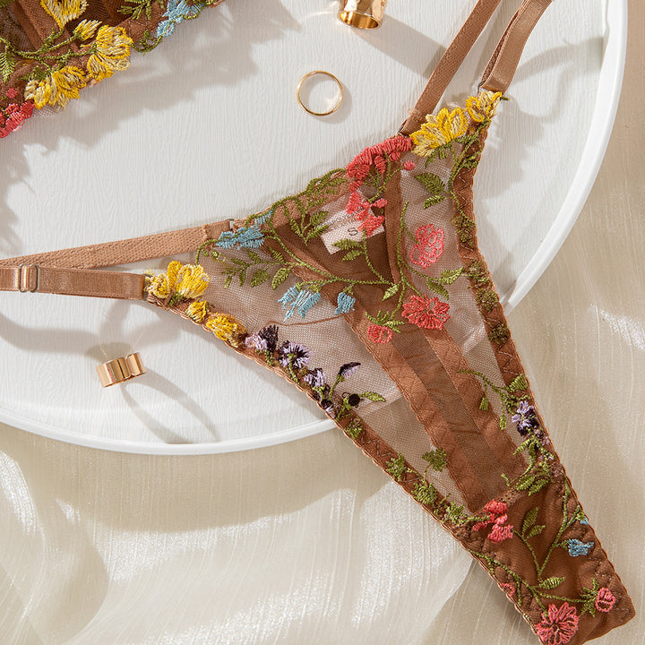 Embroidered floral sheer brown lingerie thong styled with delicate floral patterns and adjustable straps, set on a light background with gold accessories.