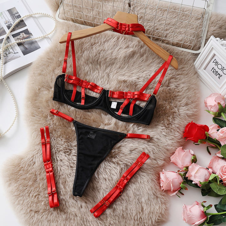 Black and red lingerie set featuring a balconette bra, matching thong, and adjustable straps, styled on soft fur with pink roses and decorative elements.