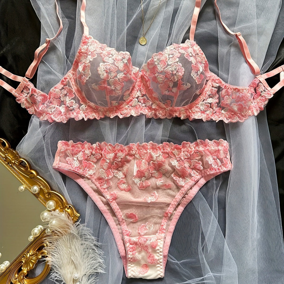 Pink floral lace lingerie set featuring a bralette with embroidered detailing and matching panties, elegantly displayed with accessories.