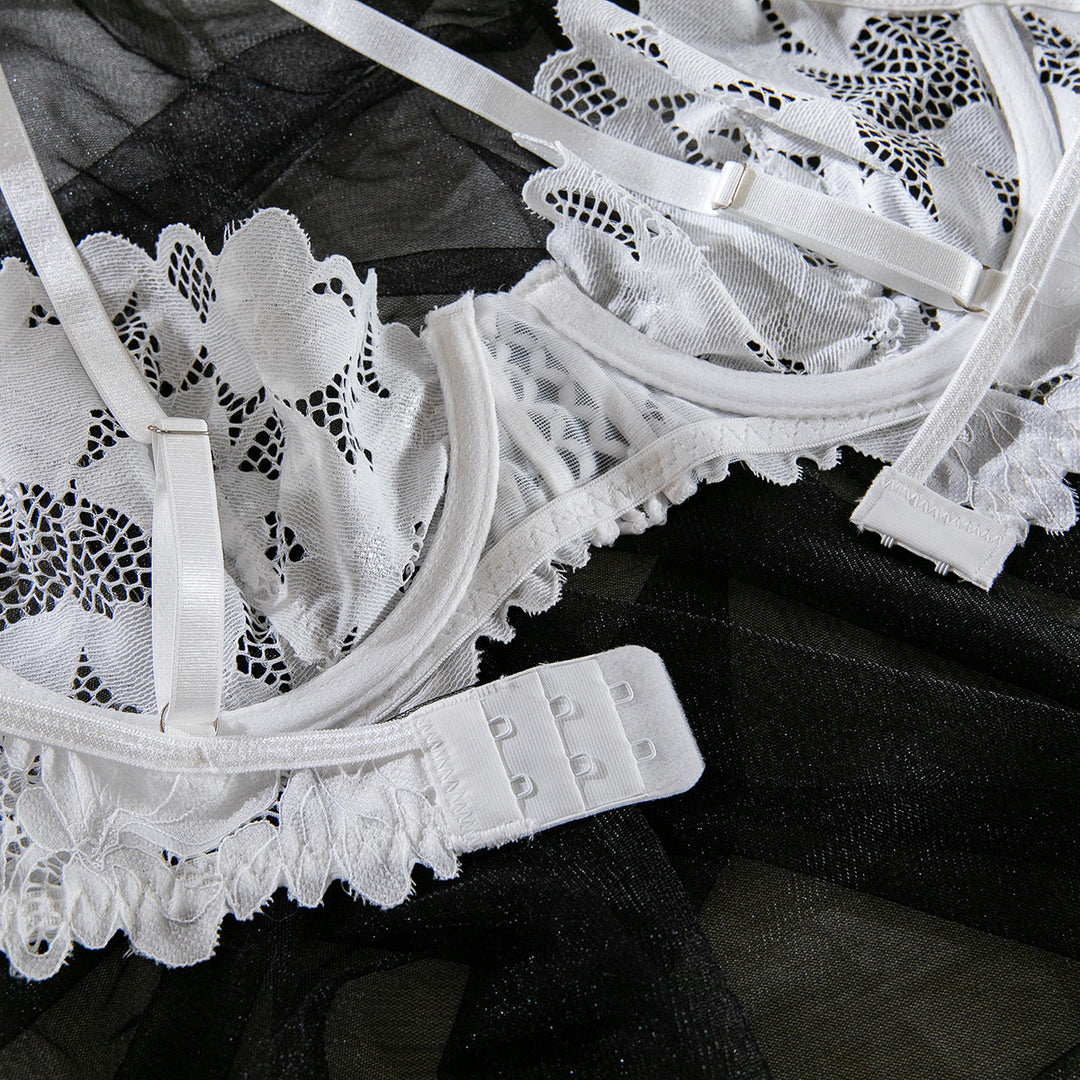 White lace bra with intricate floral design, soft straps, and adjustable back closure on a black sheer fabric background.