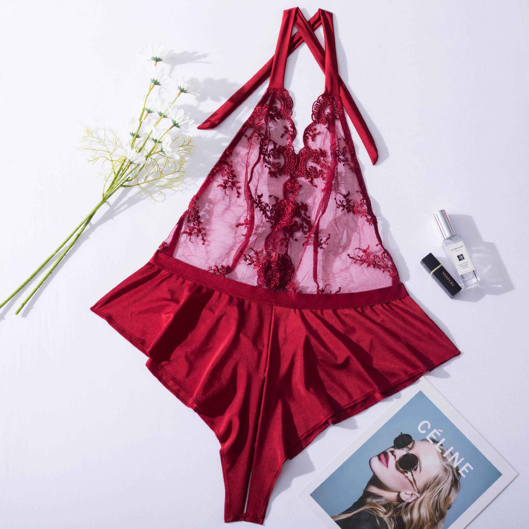 Luxe red lace chemise featuring a delicate embroidered bodice and flared hem, paired with a stylish floral arrangement and beauty products.