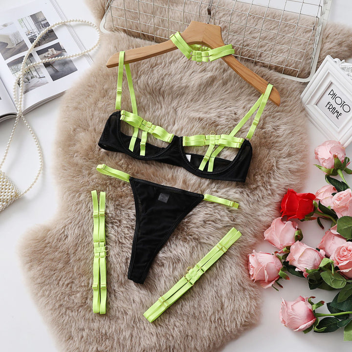 Black lingerie set featuring a bralette with vibrant green satin straps and matching thong, styled on a plush background with flowers.