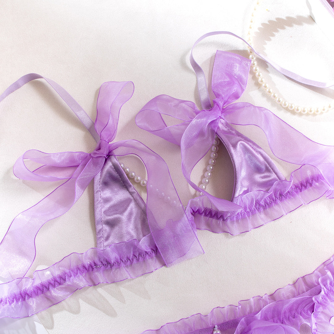 Purple satin lingerie set with sheer ruffles and bows, adorned with pearl detailing.