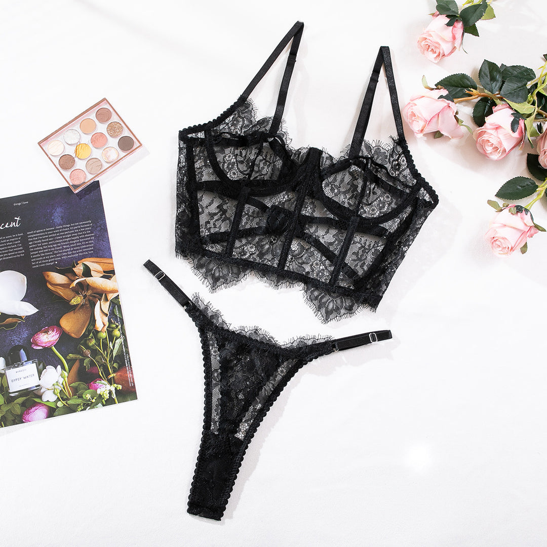 Black lace lingerie set featuring a delicate bralette with adjustable straps and a matching thong, artfully displayed on a white surface with floral accents and a makeup