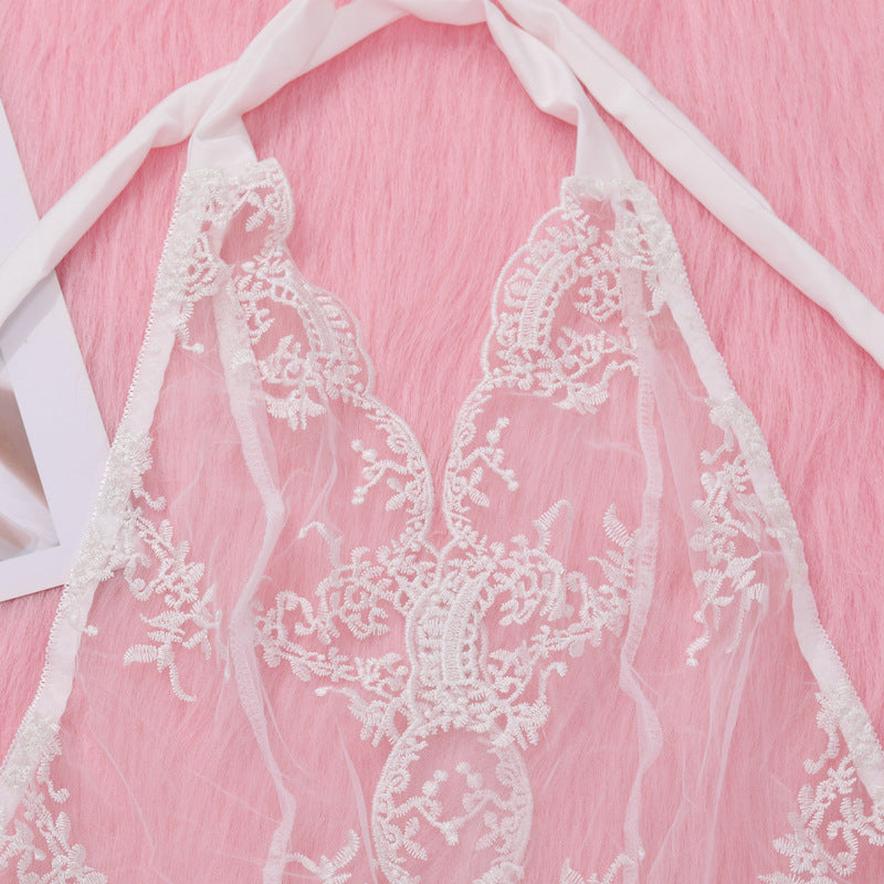 Delicate white lace lingerie featuring intricate floral embroidery and adjustable ties, displayed on a soft pink background.
