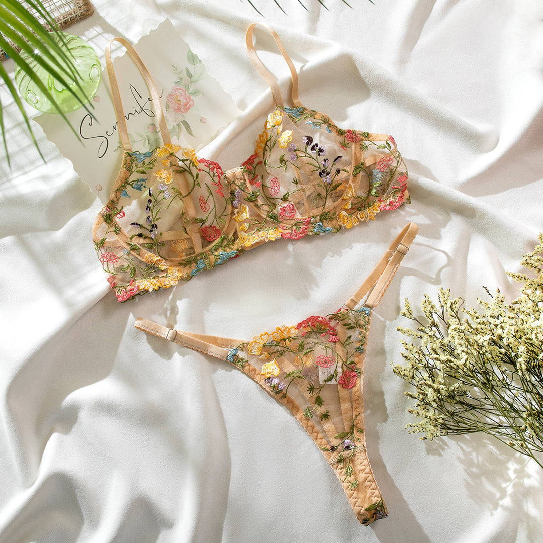 Lingerie set featuring a delicate floral embroidered bra and matching thong, designed in soft pastel shades with intricate lace detailing. The pieces are elegantly displayed on