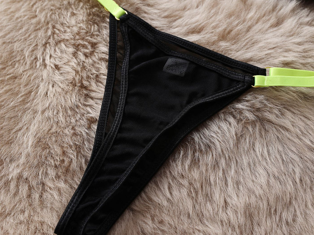 Black lace thong with neon green straps on a plush fur background.