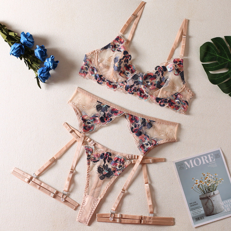 Floral embroidered lingerie set featuring a sheer bra and matching thong with adjustable straps, styled with decorative satin accents.