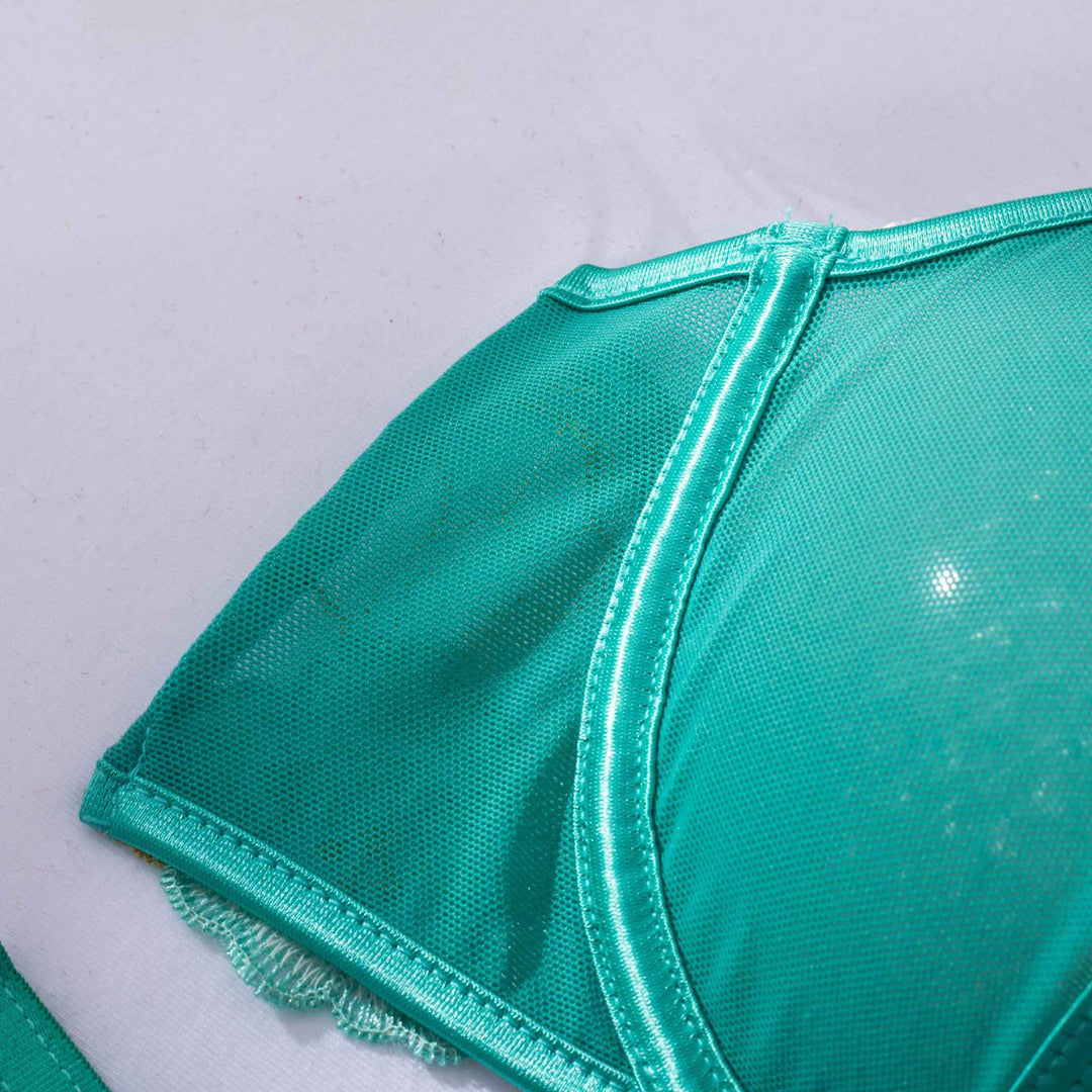 A close-up view of a luxurious green lingerie bra featuring a soft mesh design and delicate trim. The bra showcases a sleek satin finish along the edges,