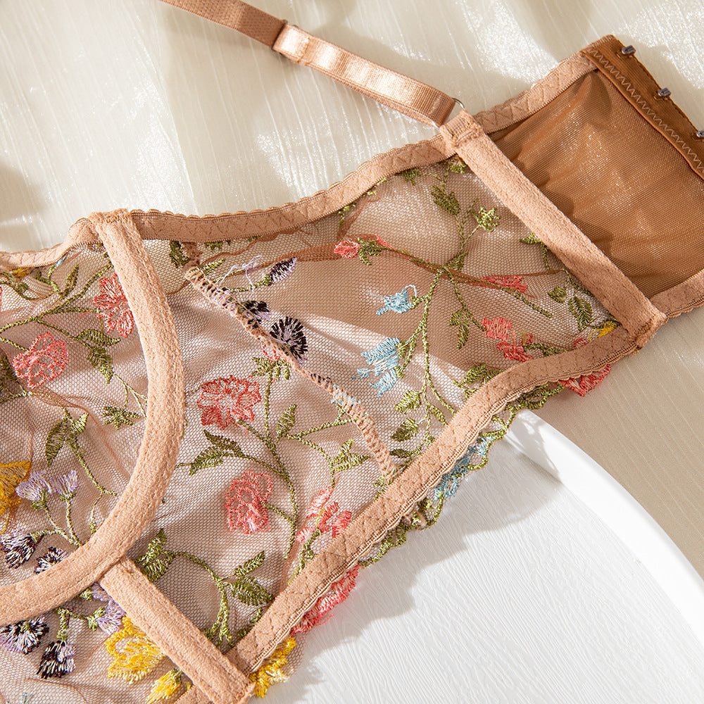 Embroidered sheer lingerie bralette with floral details and adjustable straps in a soft nude color.