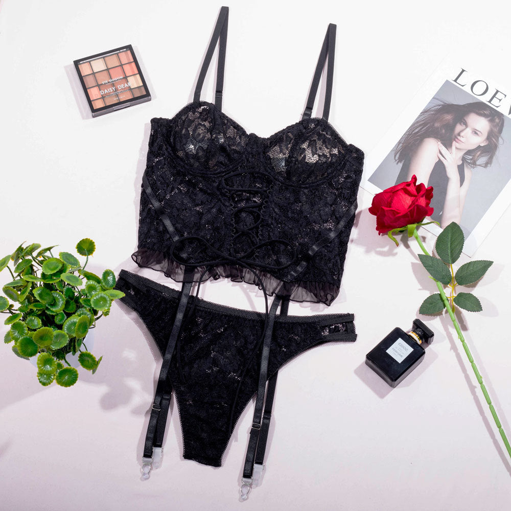 Black lace lingerie set featuring a cropped lace bralette with intricate detailing and matching thong. Styled with delicate straps, complemented by a romantic rose and elegant perfume