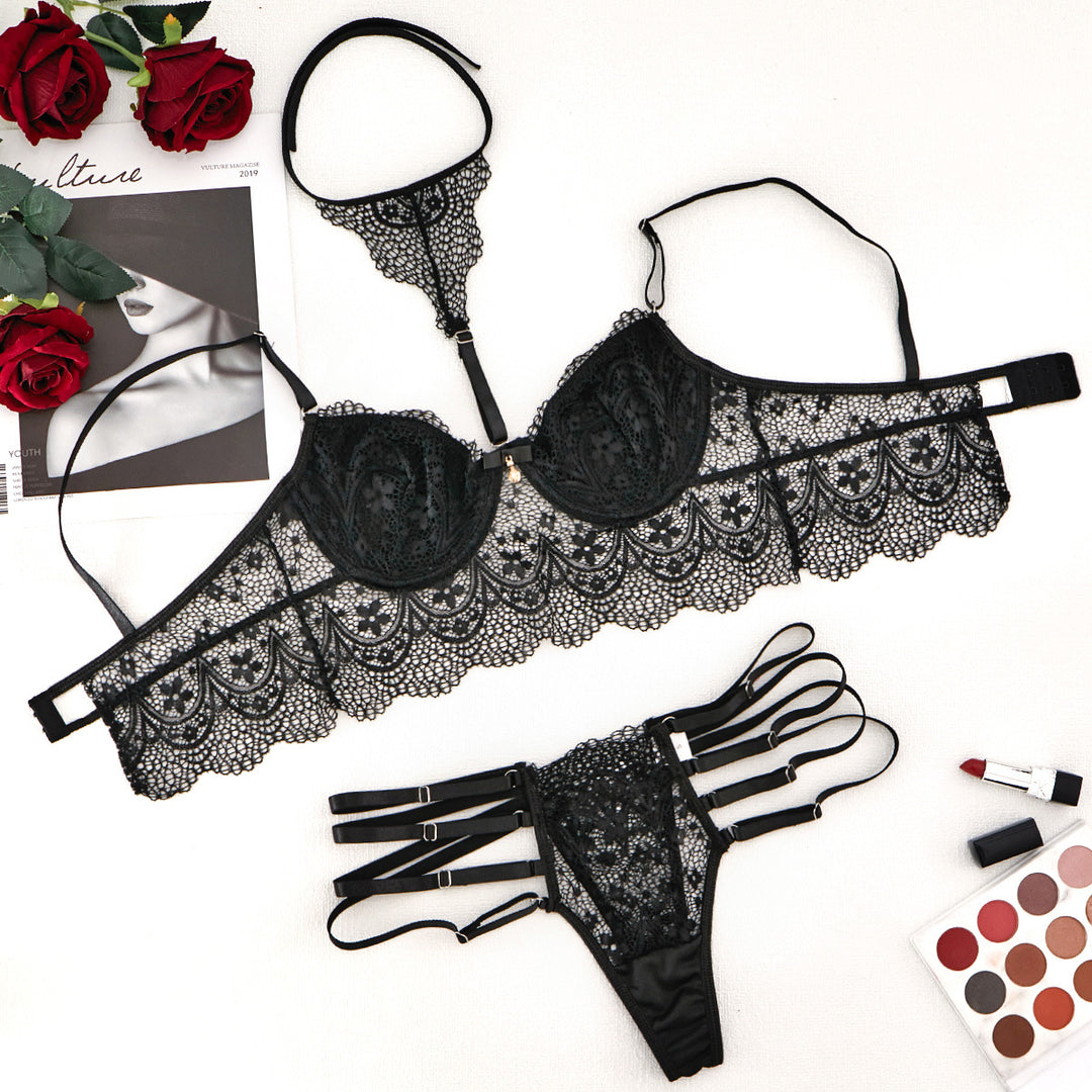 Black lace lingerie set featuring a balconette bra with scalloped edges and matching strappy thong, styled with roses and cosmetics.