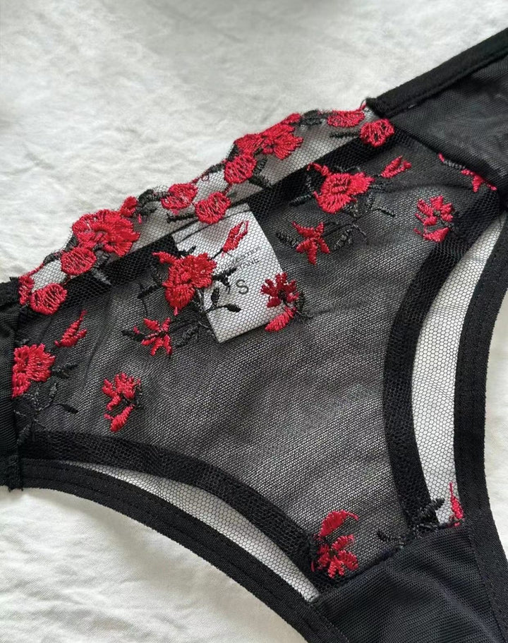 Black mesh lingerie thong with intricate red floral embroidery, showcasing a delicate and feminine design.