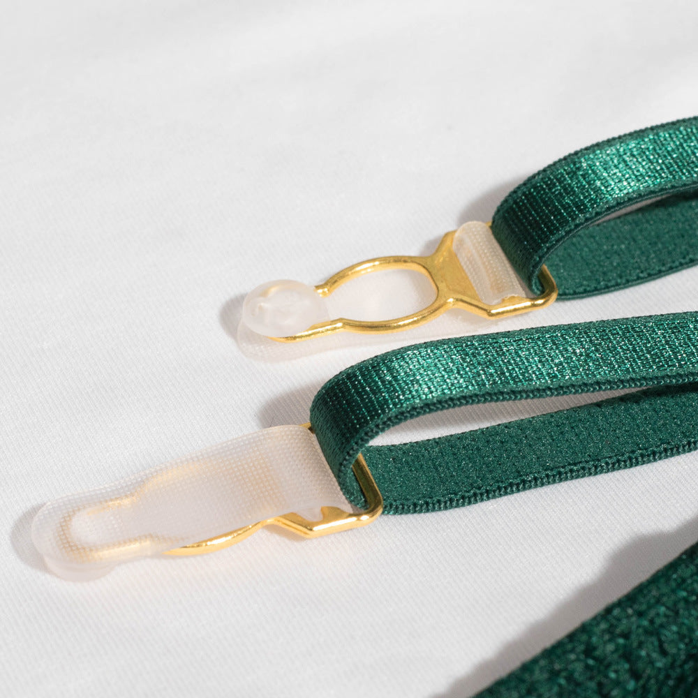 Detail of lingerie straps featuring luxurious green fabric and elegant gold hardware. The close-up showcases adjustable elements, highlighting the quality and craftsmanship of the design. Ideal