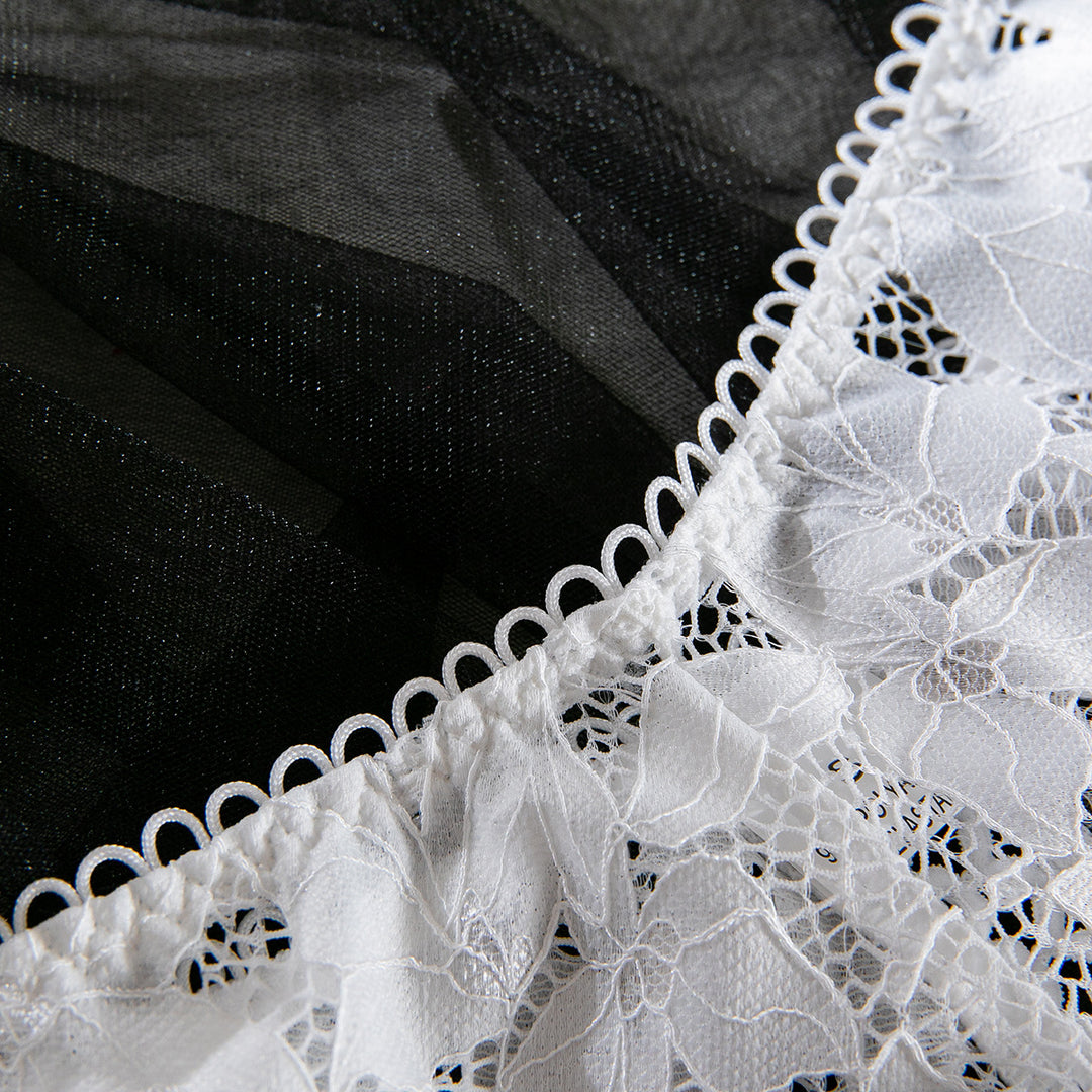 Delicate white lace detail on sheer black lingerie, featuring intricate floral patterns and elegant trim.