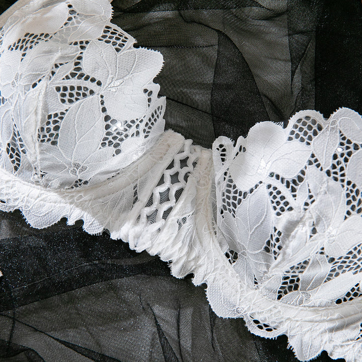 White lace bra with floral design and intricate mesh detailing, set against a sheer black background.