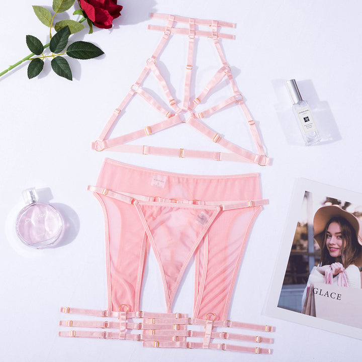 Lingerie set featuring a delicate pink strappy bralette and matching thong, adorned with gold accents. The set is styled with a rose, a