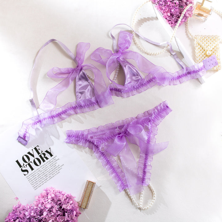 Purple sheer lingerie set featuring a delicate bralette with soft bows and frilly detailing, paired with matching panties also adorned with bows. The set is stylish