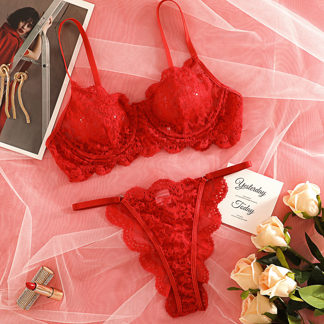 Red lace lingerie set featuring a delicate bra and matching thong, adorned with intricate floral patterns. Styled on soft tulle fabric with elegant accessories, ideal for