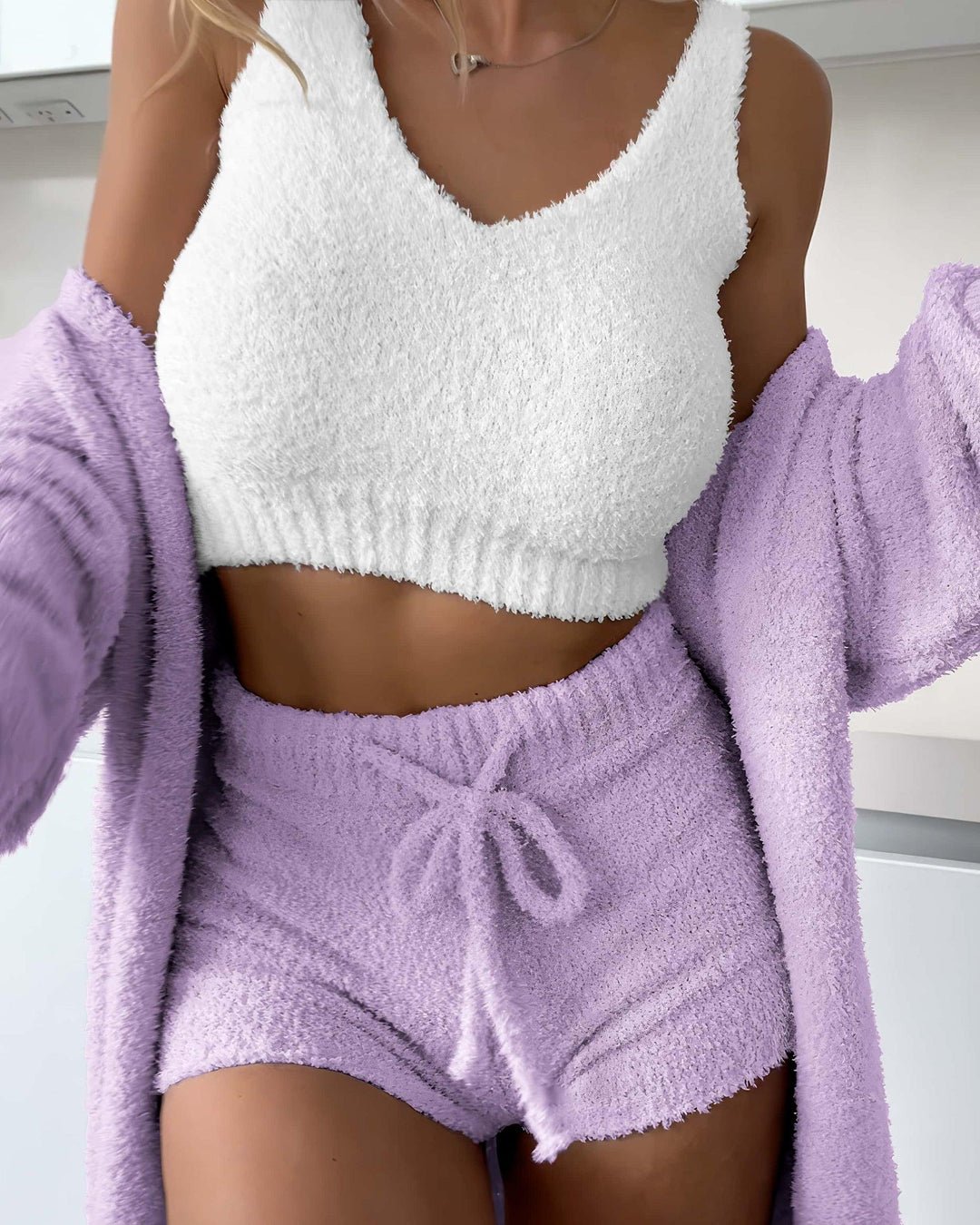 Cozy loungewear set featuring a white fluffy crop top and lilac soft shorts, perfect for relaxation and sleep.