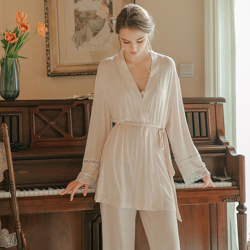 Elegant beige robe with lace details, styled with a matching pajama set, worn by a model in a cozy indoor setting.