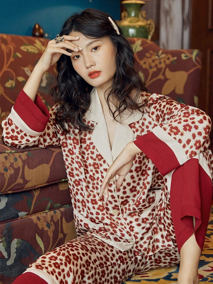 Model showcasing leopard print loungewear set with contrasting red sleeves, sitting elegantly on a patterned couch.