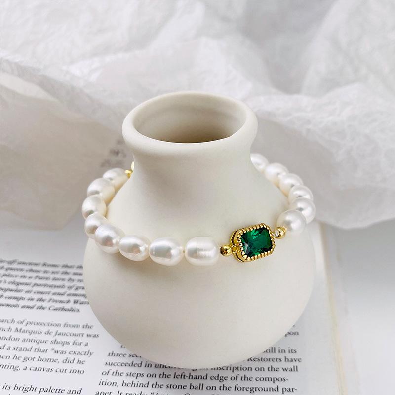 Elegant pearl bracelet featuring a central emerald gemstone, perfect for adding a touch of sophistication to any outfit.