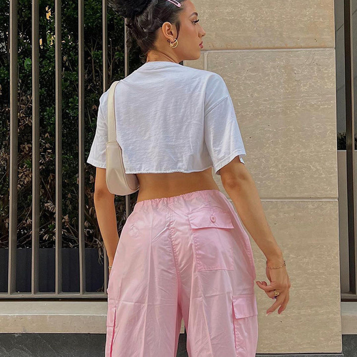 Model wearing a cropped white t-shirt and pink cargo pants, showcasing a relaxed street style look.