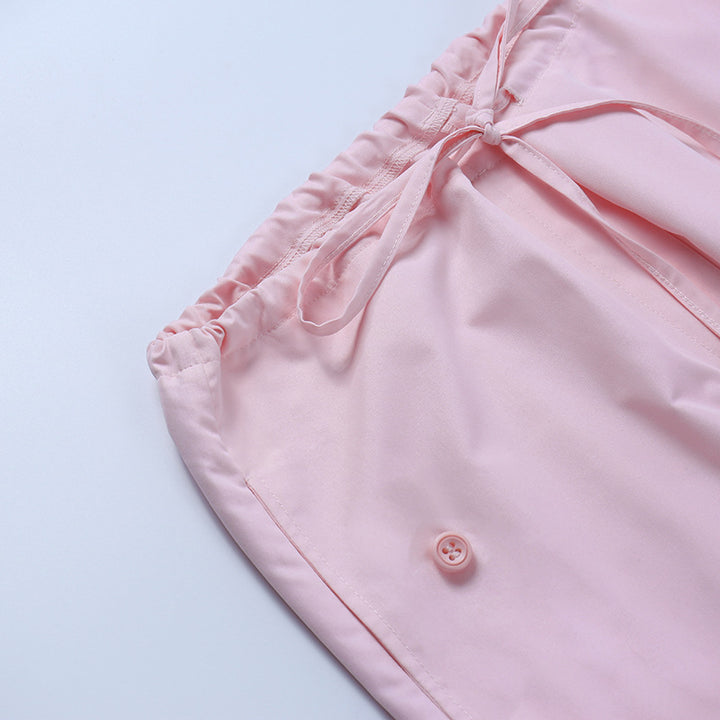 Light pink satin pajama shorts featuring an elastic waistband, drawstring details, and a button closure.