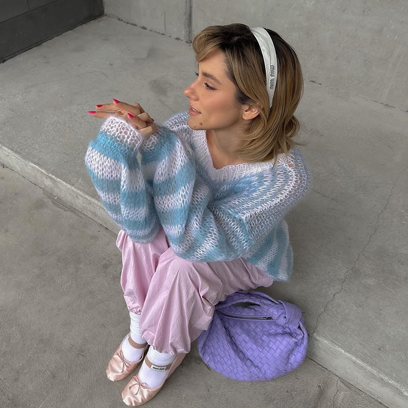 Model seated on the floor wearing a blue and white striped knit sweater and pink lounge pants, with a lavender handbag and ballet flats, showcasing a cozy and stylish nightwear look.