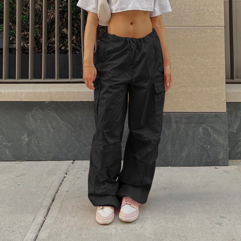 Black cargo pants with an elastic waistband, styled with a cropped white top and paired with pink sneakers, showcasing a trendy urban look.