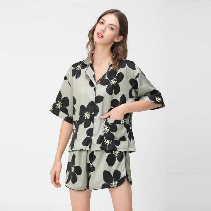 Floral print satin pajama set featuring a short-sleeve button-up top and matching shorts in soft green and black colors.