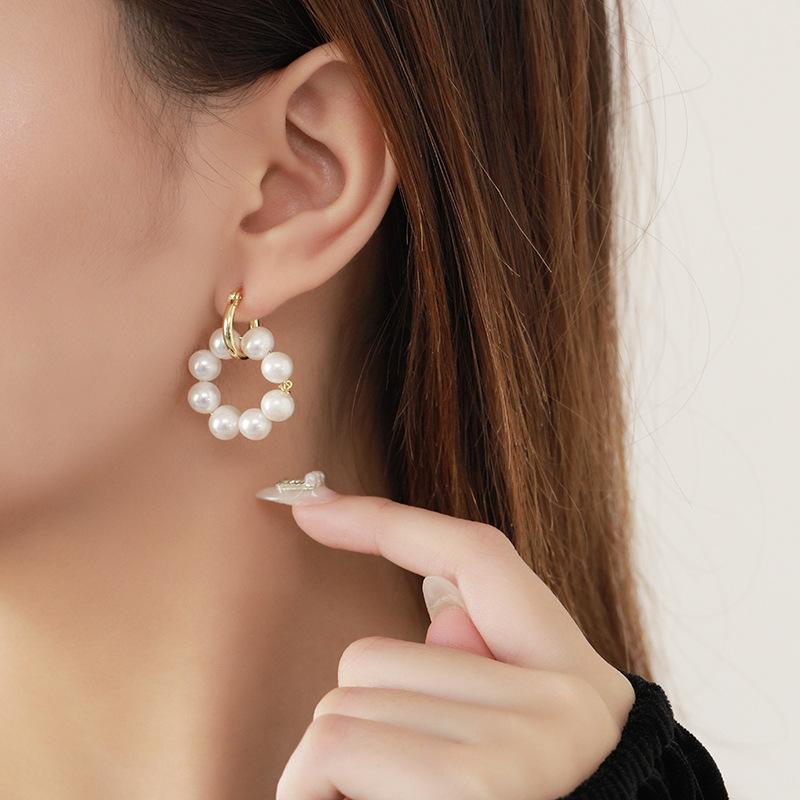 Pearl hoop earrings with gold accents showcased on a model's ear, highlighting elegant design and styling.