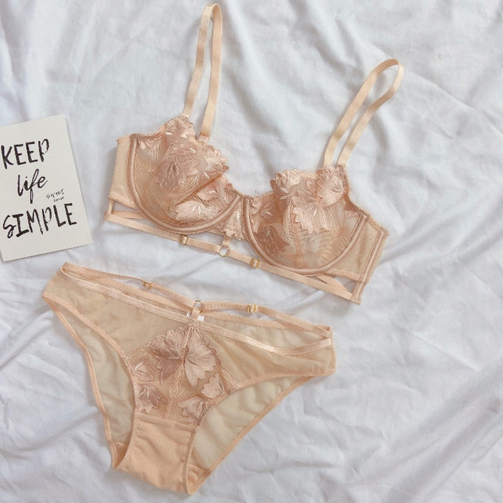 Delicate floral embroidered lingerie set featuring a soft bra and matching panties in a sheer peach color, styled on a light background with a motivational card.