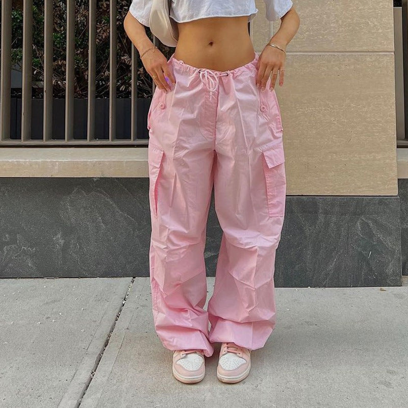 Pink cargo pants with a drawstring waist, styled with a cropped white top and pink sneakers.