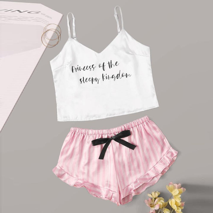 White satin cami top with "Princess of the sleepy kingdom" print paired with pink striped shorts featuring a black bow.