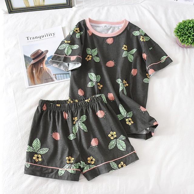 Relax in style with this cozy two-piece pajama set featuring a short-sleeved top and matching shorts, adorned with vibrant floral and strawberry prints on a dark background. Perfect for comfortable nights and lounging.