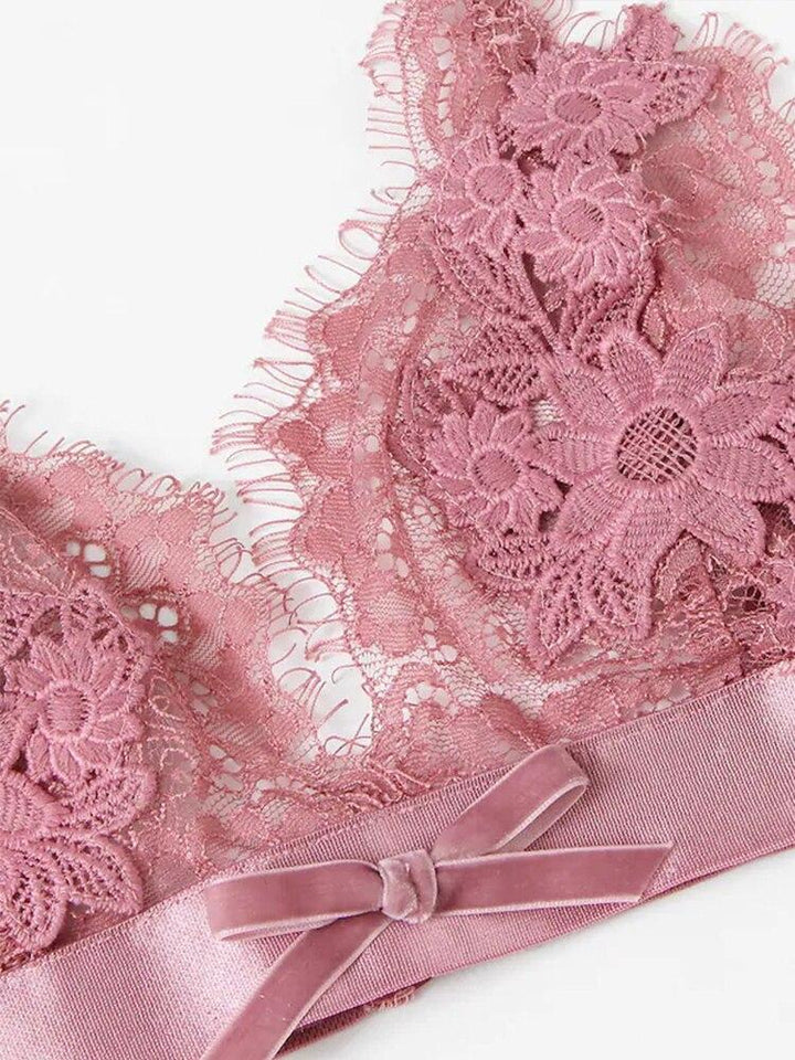 Lace bralette in soft pink with floral embroidery and a satin bow detail, perfect for a feminine and luxurious touch.